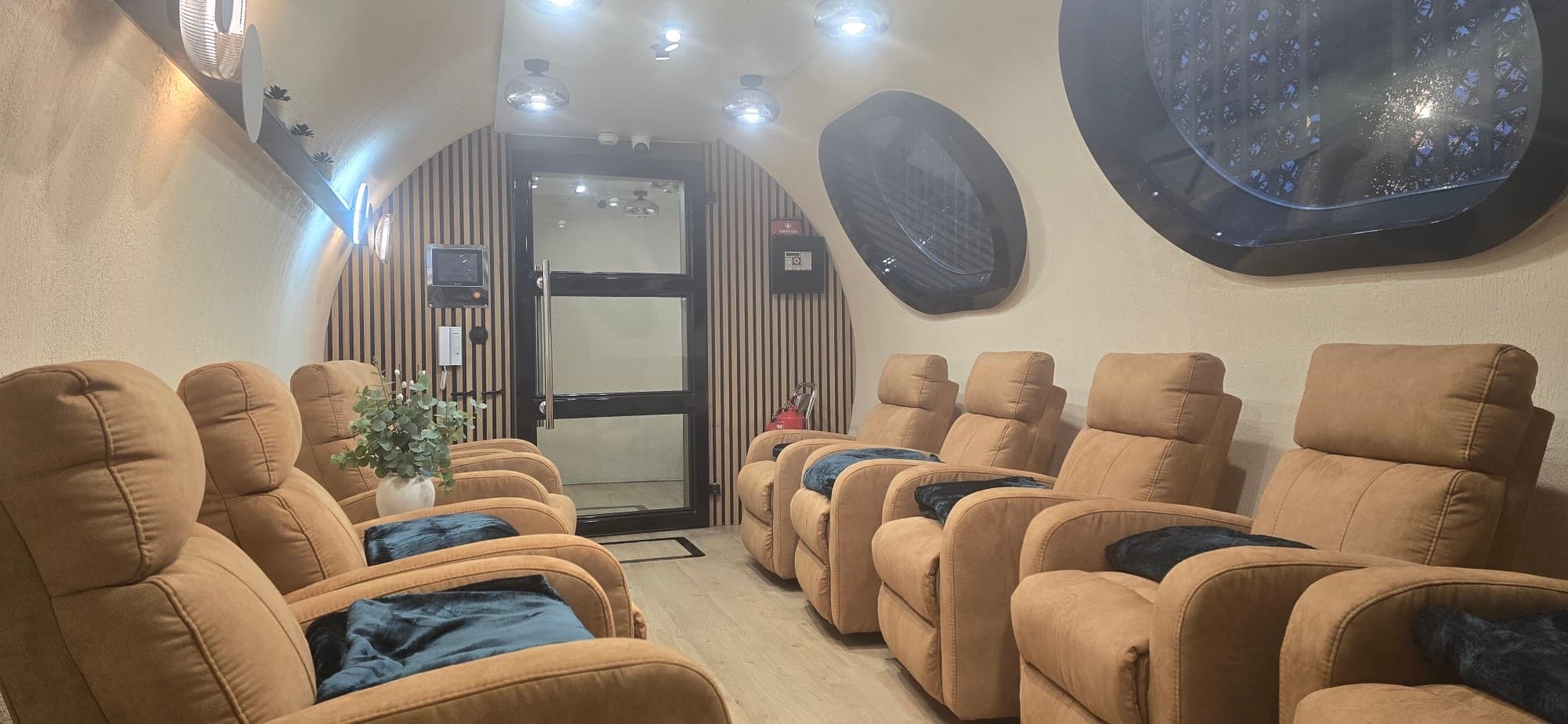 Inside the Oxygen Oasis chamber: recliners with blankets along both sides, porthole windows and the door